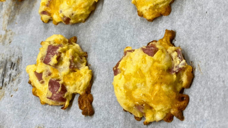 Golden keto ham and cheese bites on a parchment-lined baking sheet
