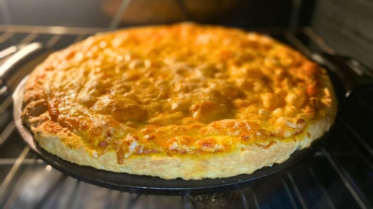 Golden homemade cheese pizza baking on a pan in the oven