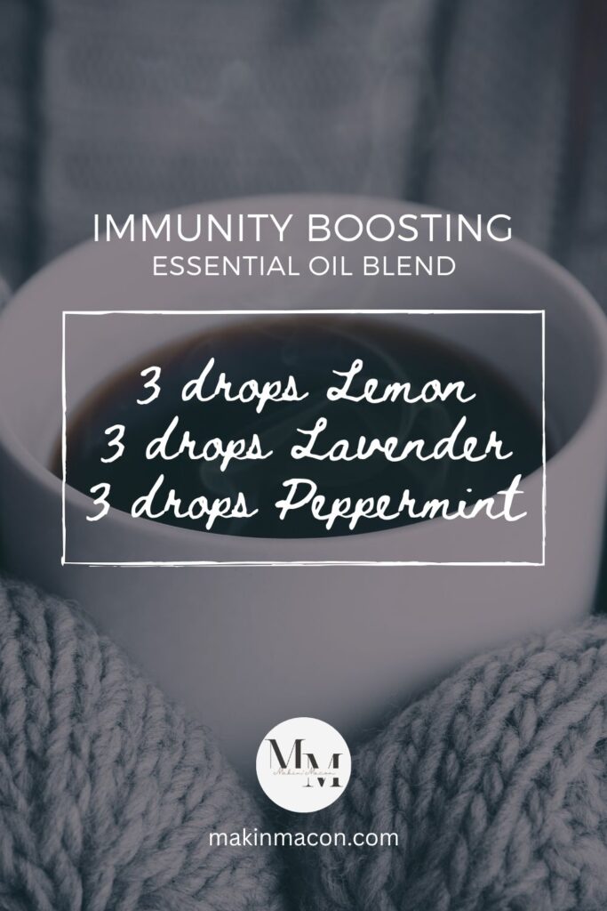 Immunity Boosting Essential Oil Blend pin with a handwritten-style recipe: 3 drops Lemon, 3 drops Lavender, 3 drops Peppermint, displayed over a steaming mug held in gray knit gloves.