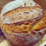 Crusty loaf of no-knead rustic bread on a wooden cutting board
