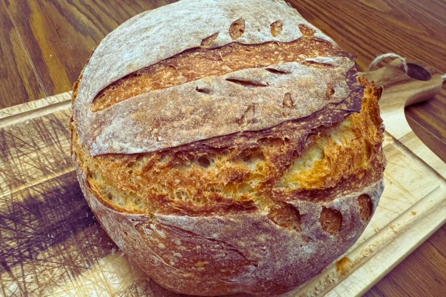 Crusty loaf of no-knead rustic bread on a wooden cutting board