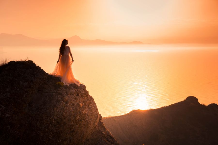 Woman standing on a cliff at sunrise reflecting on identity and faith who am I