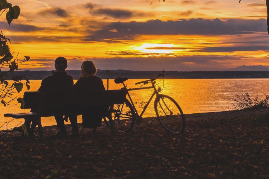 Couple sitting by the water at sunset reflecting on gratitude in every season