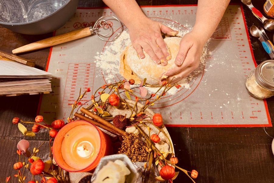 Hands kneading dough with cozy decorations for holiday baking ideas