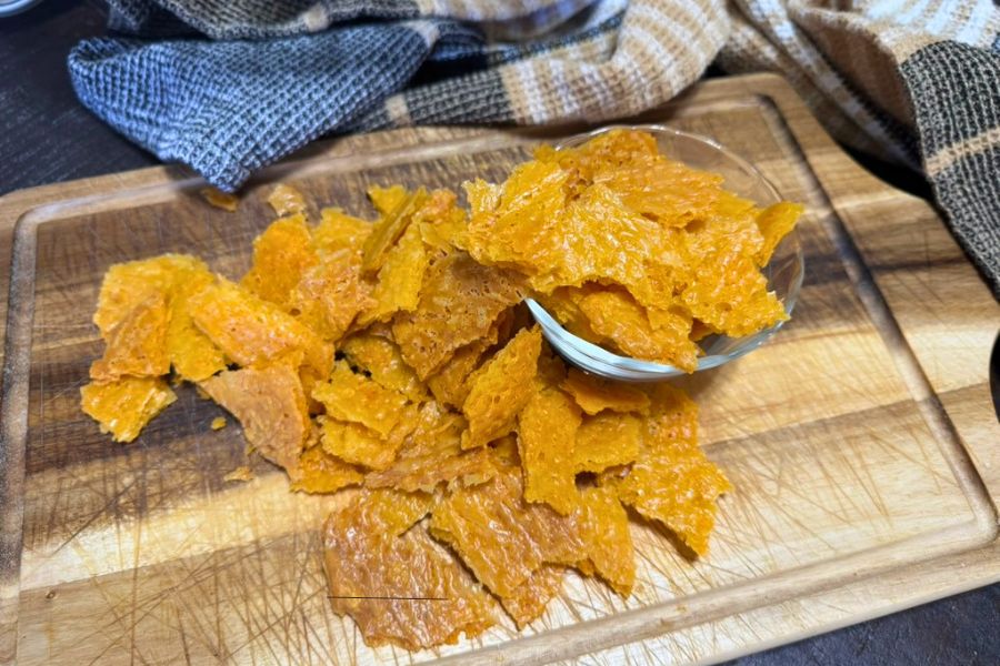 Crispy sourdough discard cheese crackers served on a wooden board with a small bowl