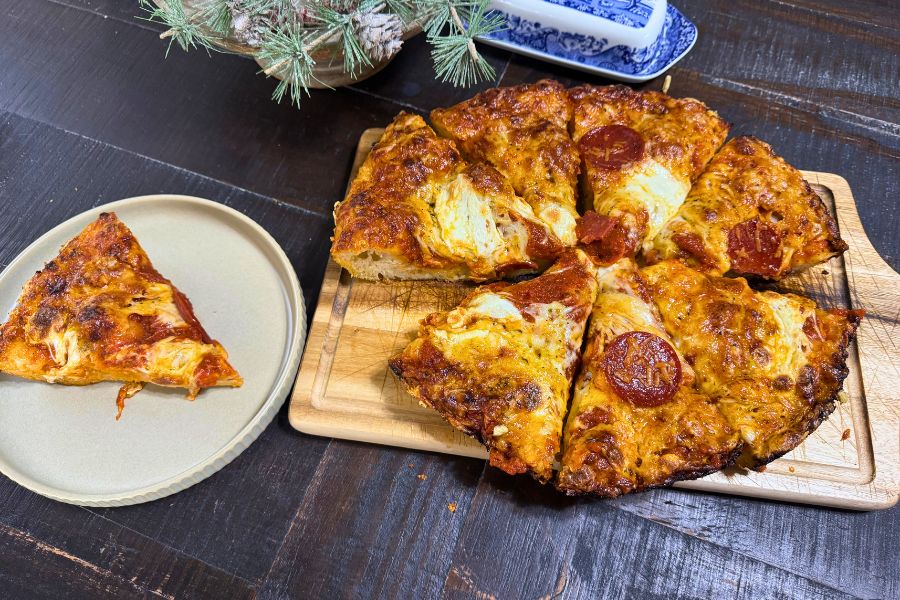 Sourdough focaccia pizza with melted cheese and pepperoni slices served on a wooden board