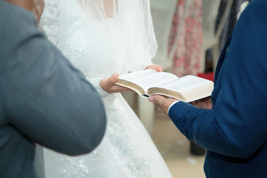 Bride and groom holding a Bible during a wedding ceremony symbolizing a Christ-centered marriage