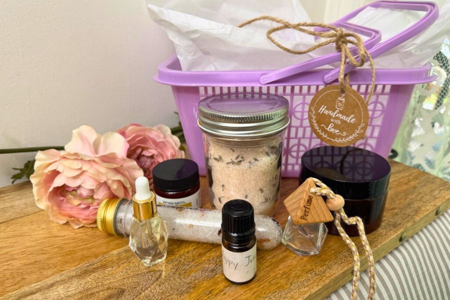 A beautiful flat lay of a handmade essential oil gift set featuring bath salts, sugar scrub, foot soak, and Simply Earth products, perfect for Mother’s Day.