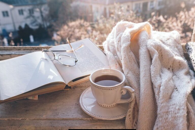 Cozy Bible study scene with open book, reading glasses, a cup of tea, and a knit blanket in warm morning light—ideal setting for a peaceful diffuser blend.