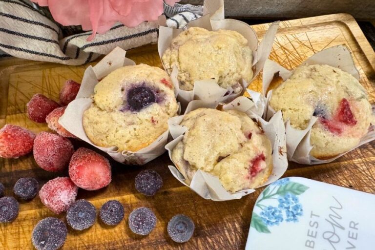Sourdough muffins with blueberries and strawberries on a wooden board with parchment liners