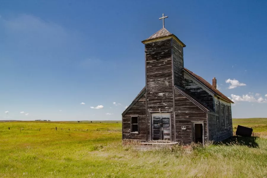 An old rural church standing alone in an open field, symbolizing reflection, obedience, and refocusing on God’s Kingdom.
