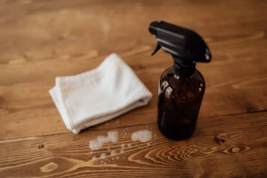 Essential oil floor cleaner in amber spray bottle on wood floor with microfiber cloth for spring cleaning