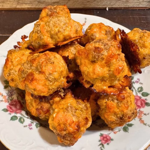 Close-up of homemade low-carb sausage balls baked until golden brown with melted cheddar cheese.