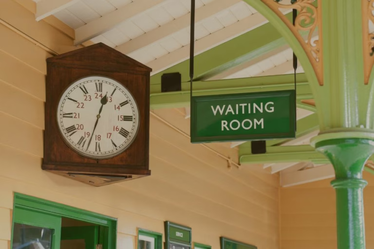 Vintage station clock beside a sign reading “Waiting Room,” symbolizing seasons of waiting, faith, trust, and God’s timing during life’s uncertain journeys.